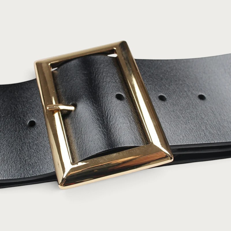 Gros plan sur la grosse boucle rectangulaire dorée et le cuir noir de la ceinture large Ceintura