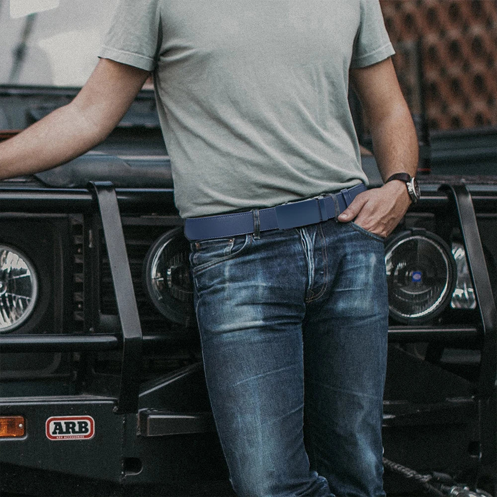 Homme en t-shirt gris et jean portant la ceinture Ceintura Viterbo, adossé à un véhicule tout-terrain