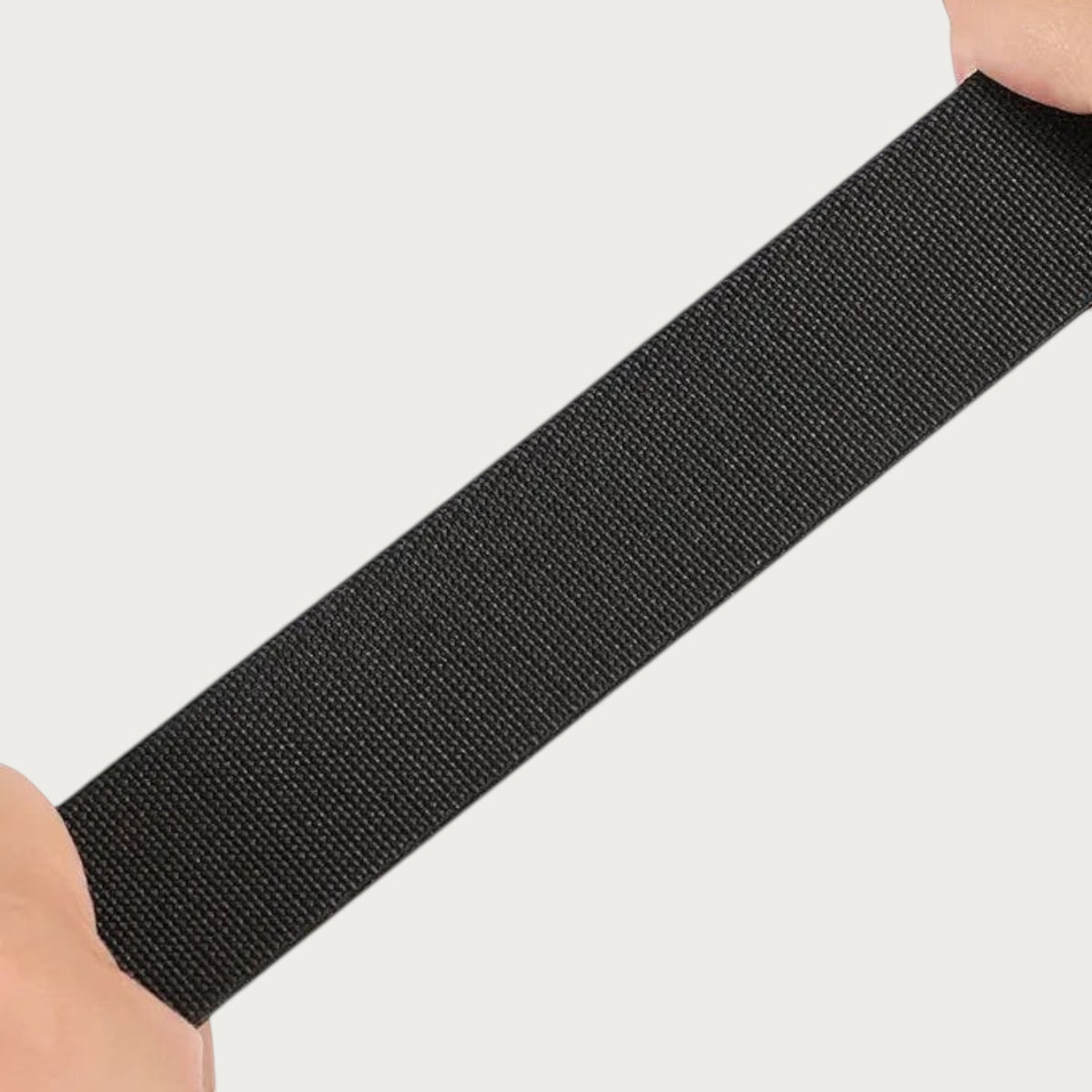 Sangle élastique noire de la ceinture Ceintura Dario étirée à la main pour montrer son extensibilité