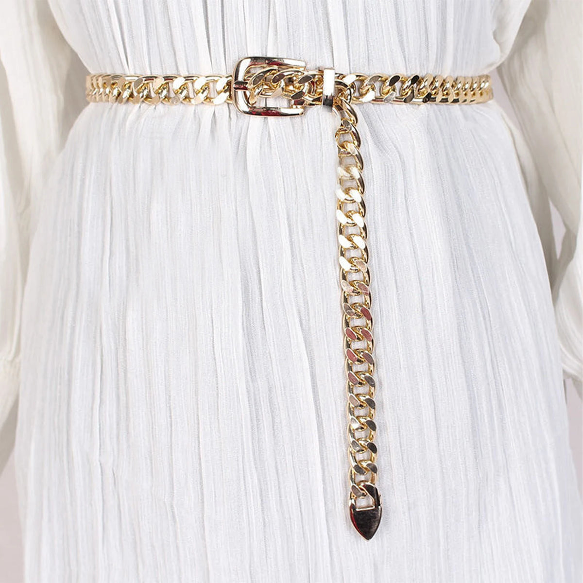 Ceinture chaîne Ceintura dorée portée sur une robe blanche, boucle ardillon et embout pointu pendant Image