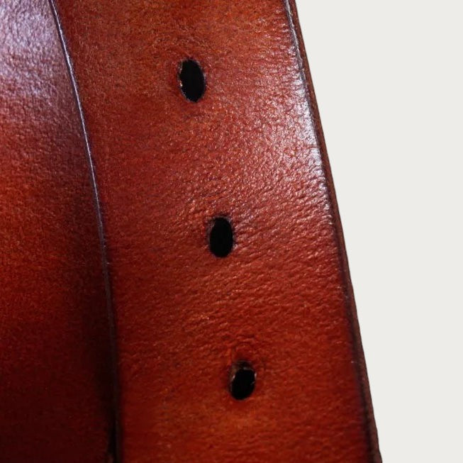 Gros plan sur le cuir de vachette acajou et les trous de réglage de la ceinture Ceintura Vittoria