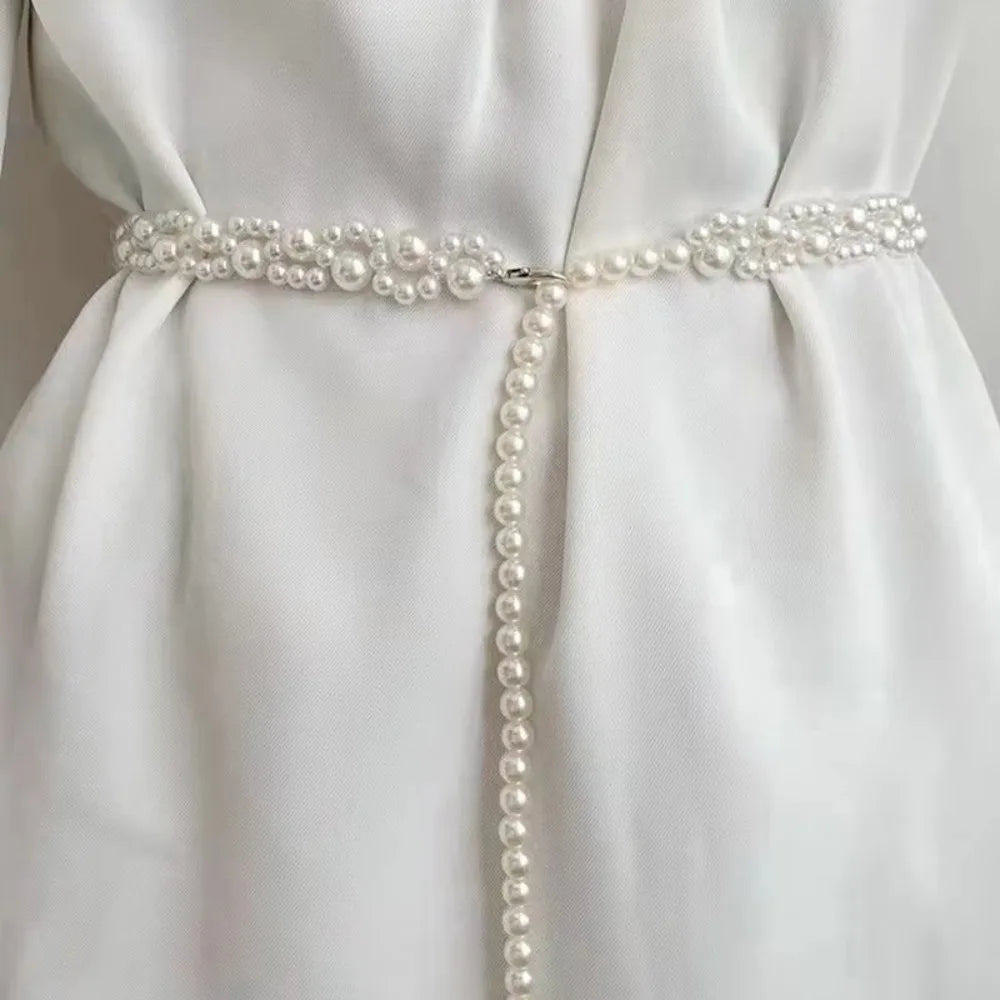 Ceinture bijoux Ceintura en perles blanches entrelacées portée sur une robe blanche à la taille Image