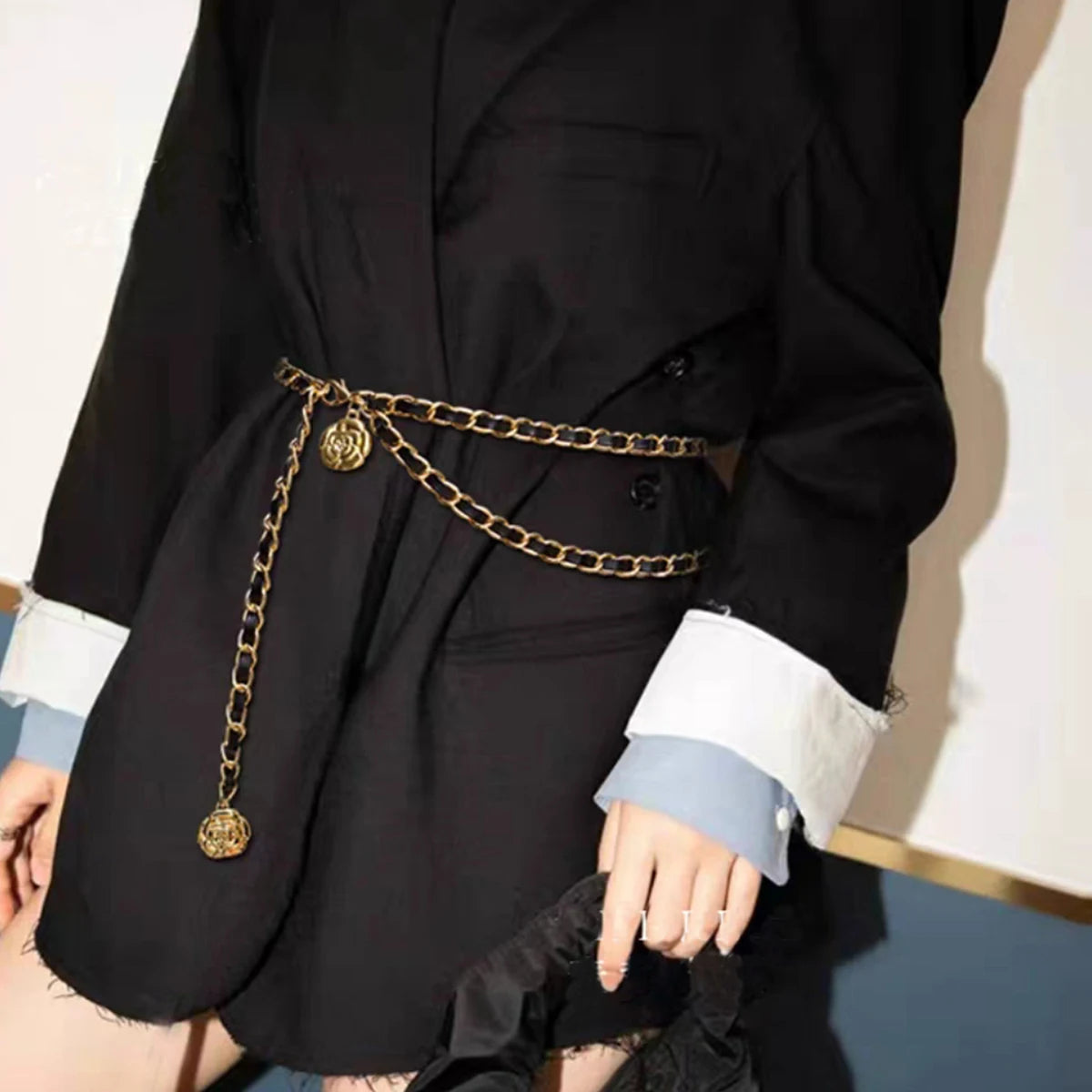 Ceinture chainette Ceintura dorée portée sur un blazer noir, pendentifs médaillons retombant sur le côté