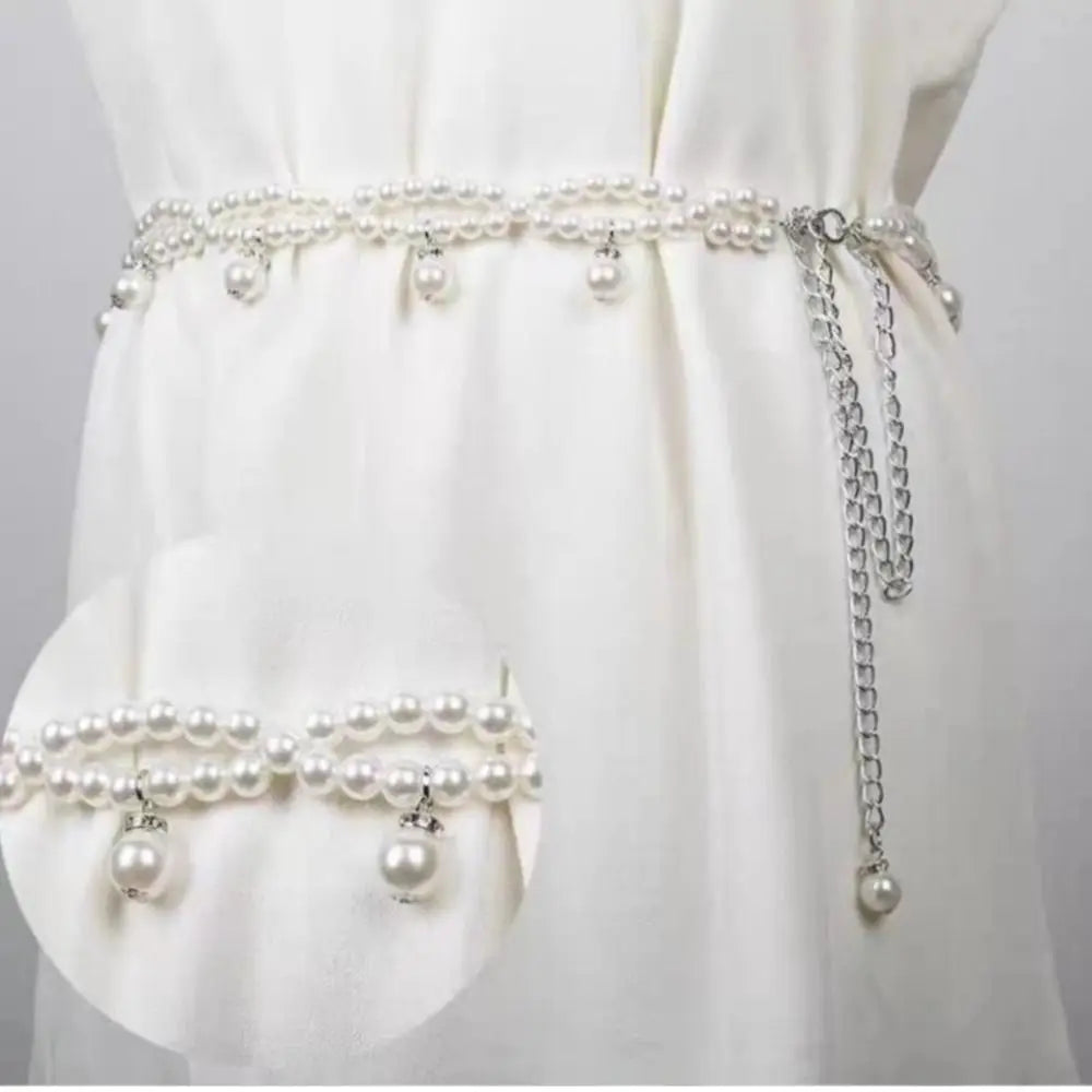 Ceinture bijoux Ceintura Perla en perles nacrées portée sur une robe blanche, pampilles et chaînette pendantes