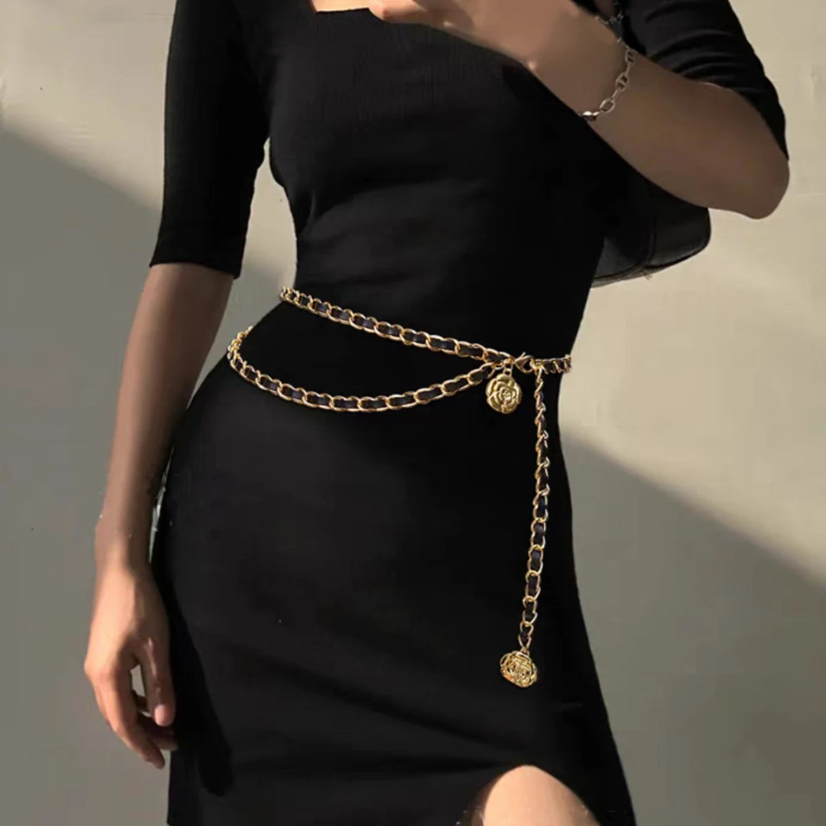 Ceinture chainette Ceintura dorée double rang portée sur une robe noire moulante avec médaillon pendant