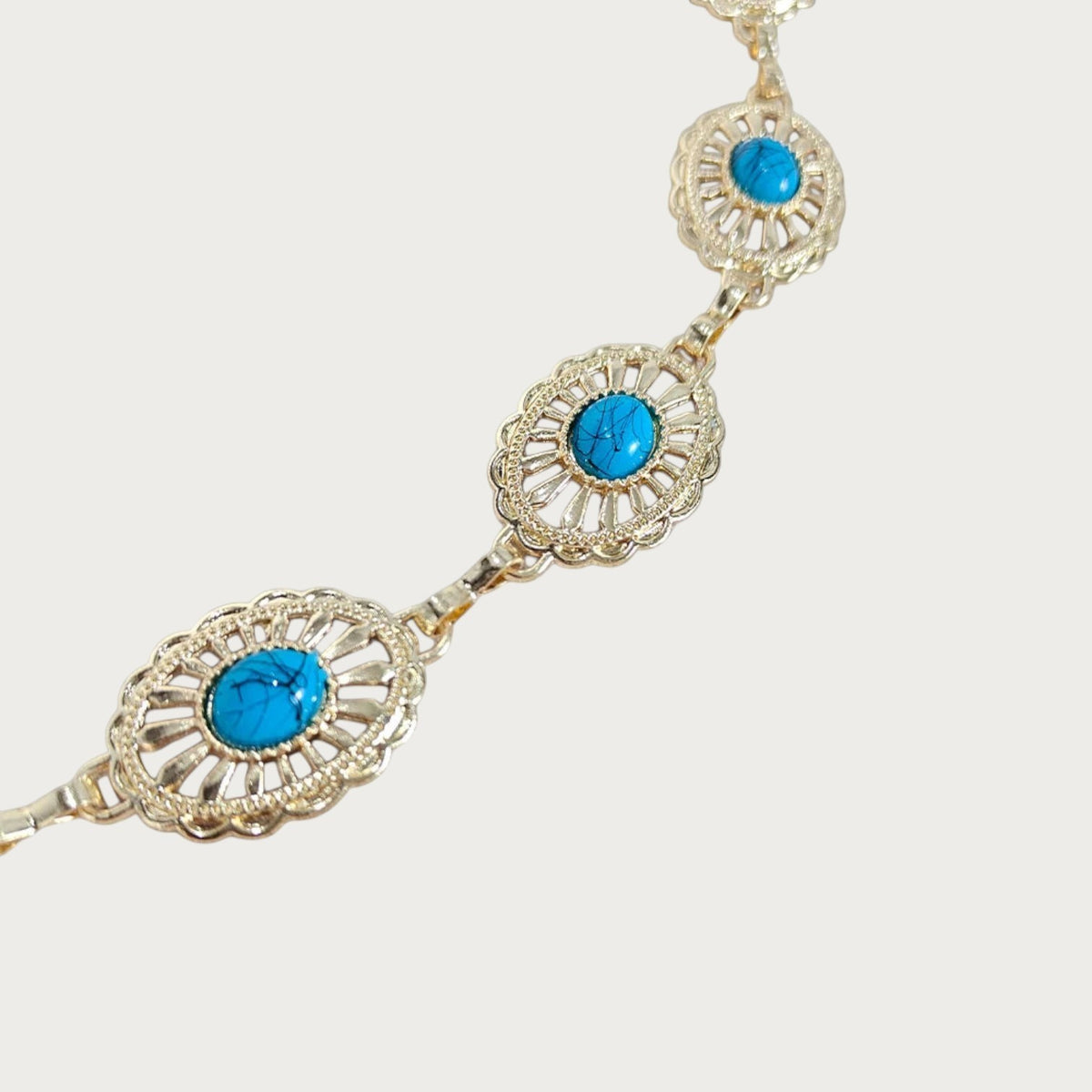 Gros plan sur deux médaillons dorés festonnés à cabochons turquoise de la ceinture Ceintura Preziosa Image