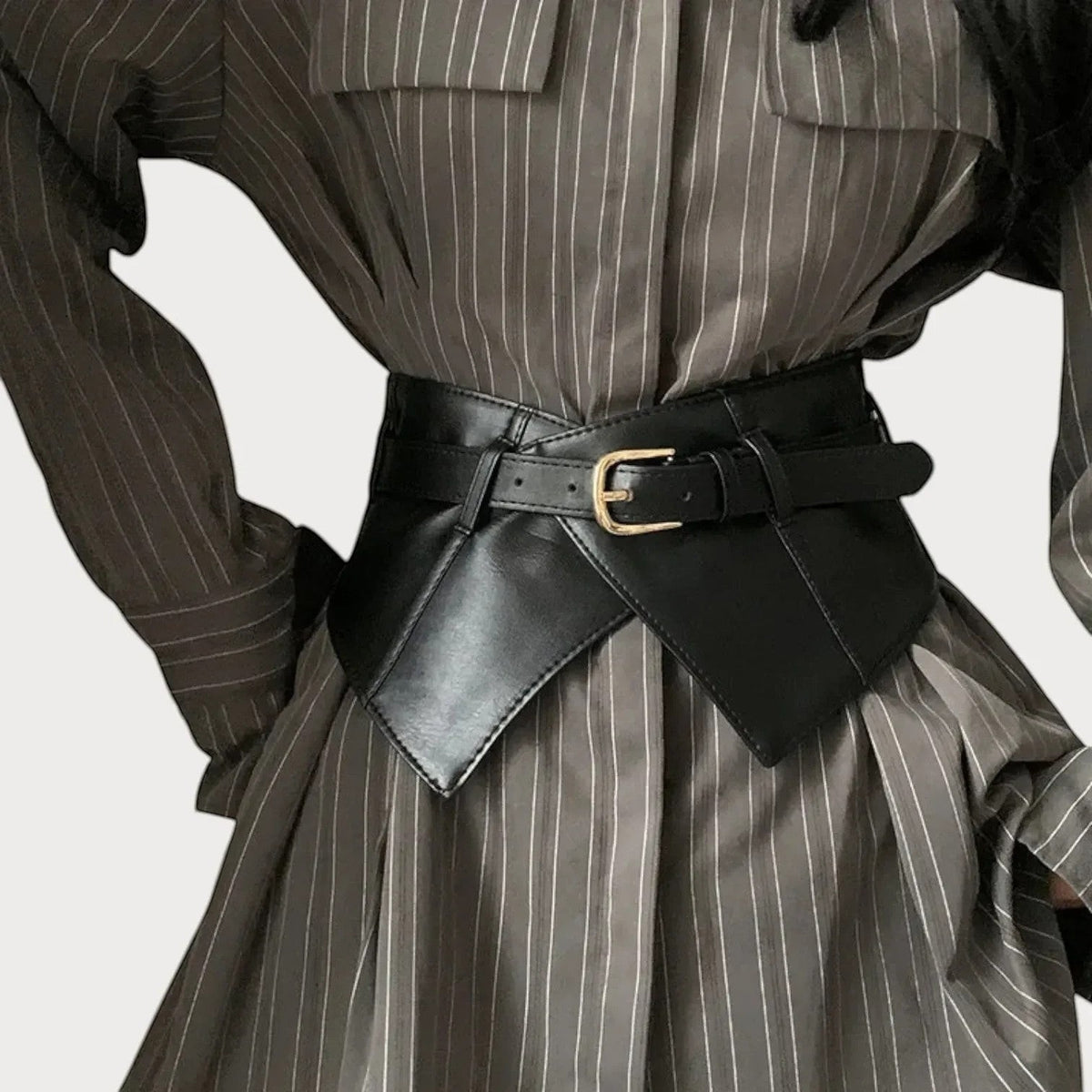 Ceinture large Ceintura style corset en similicuir noir avec boucle dorée portée sur une robe rayée