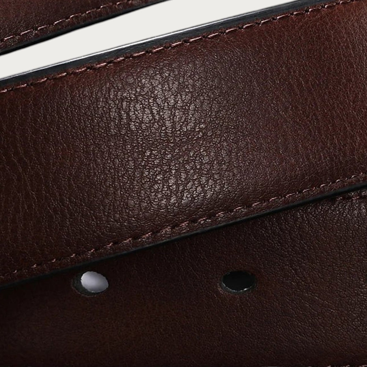 Gros plan sur la texture en cuir de vachette marron de la ceinture réversible Ceintura avec surpiqûres ton sur ton