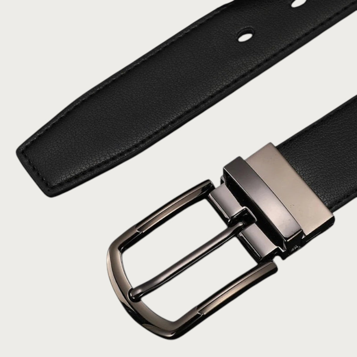 Gros plan en diagonale sur la boucle rotative gris acier et le cuir noir grainé de la ceinture Ceintura Dante
