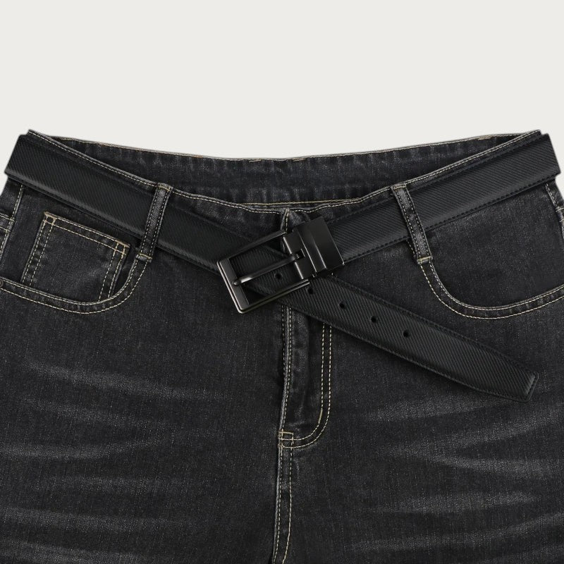 Ceinture réversible pour homme en cuir fendu noir avec boucle rotative, portée sur un jean denim foncé. Image