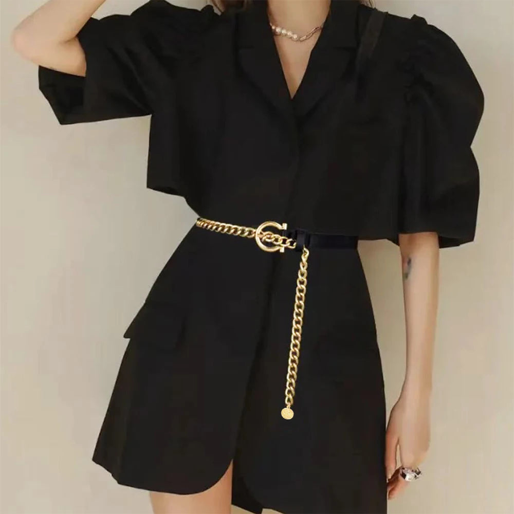 Ceintura ceinture femme noire en similicuir avec chaîne dorée et boucle géométrique élégante sur une robe noire