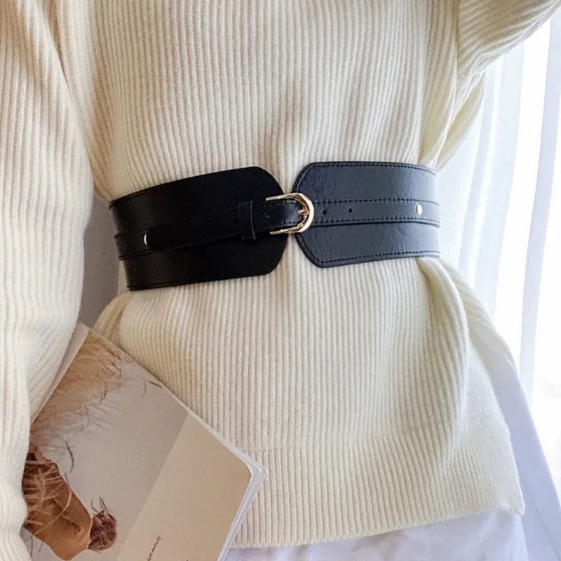 Ceinture large Ceintura style corset en similicuir noir avec boucle dorée portée sur un pull blanc