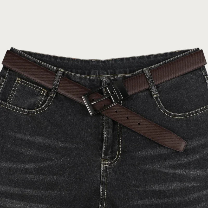 Ceinture réversible pour homme en cuir fendu marron avec boucle rotative noire portée sur un jean noir