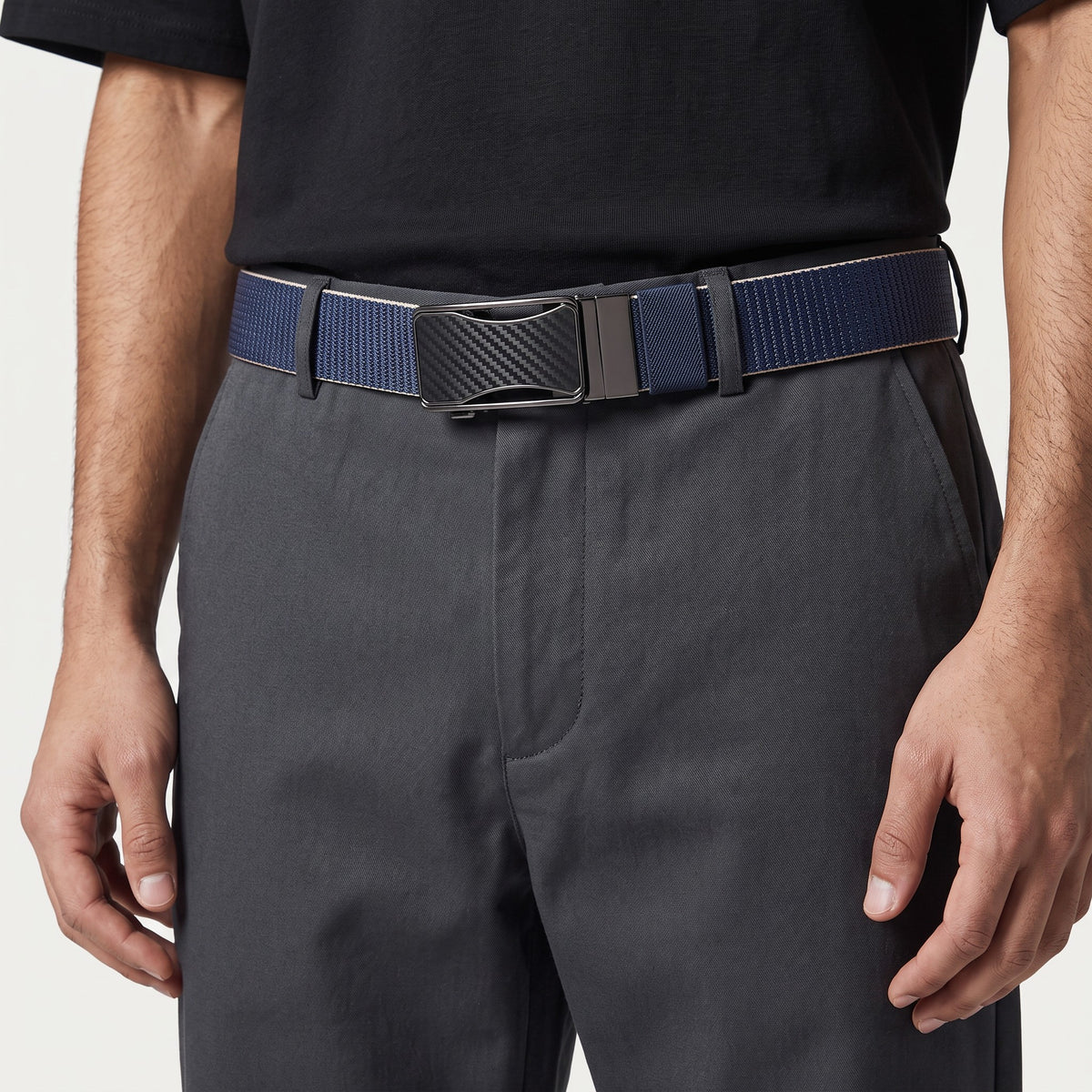 Ceinture réversible Ceintura Ettore en toile bleue avec boucle plaque noire mate portée sur un pantalon gris