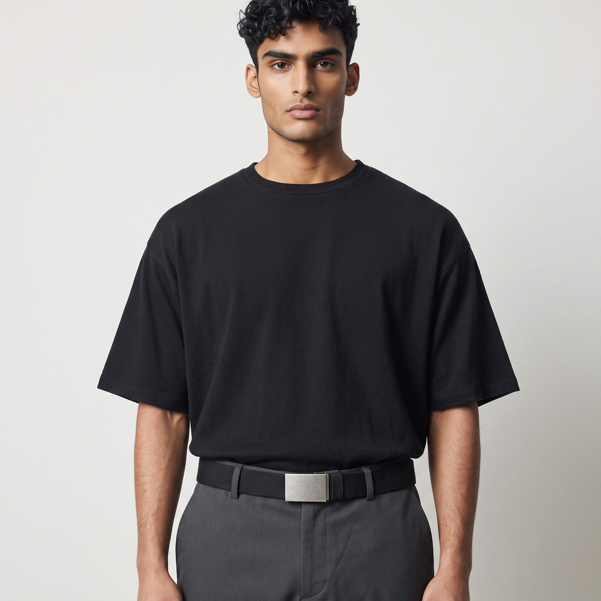 Homme portant la ceinture réversible en toile Ceintura Carlo avec boucle plaque argentée sur un pantalon gris