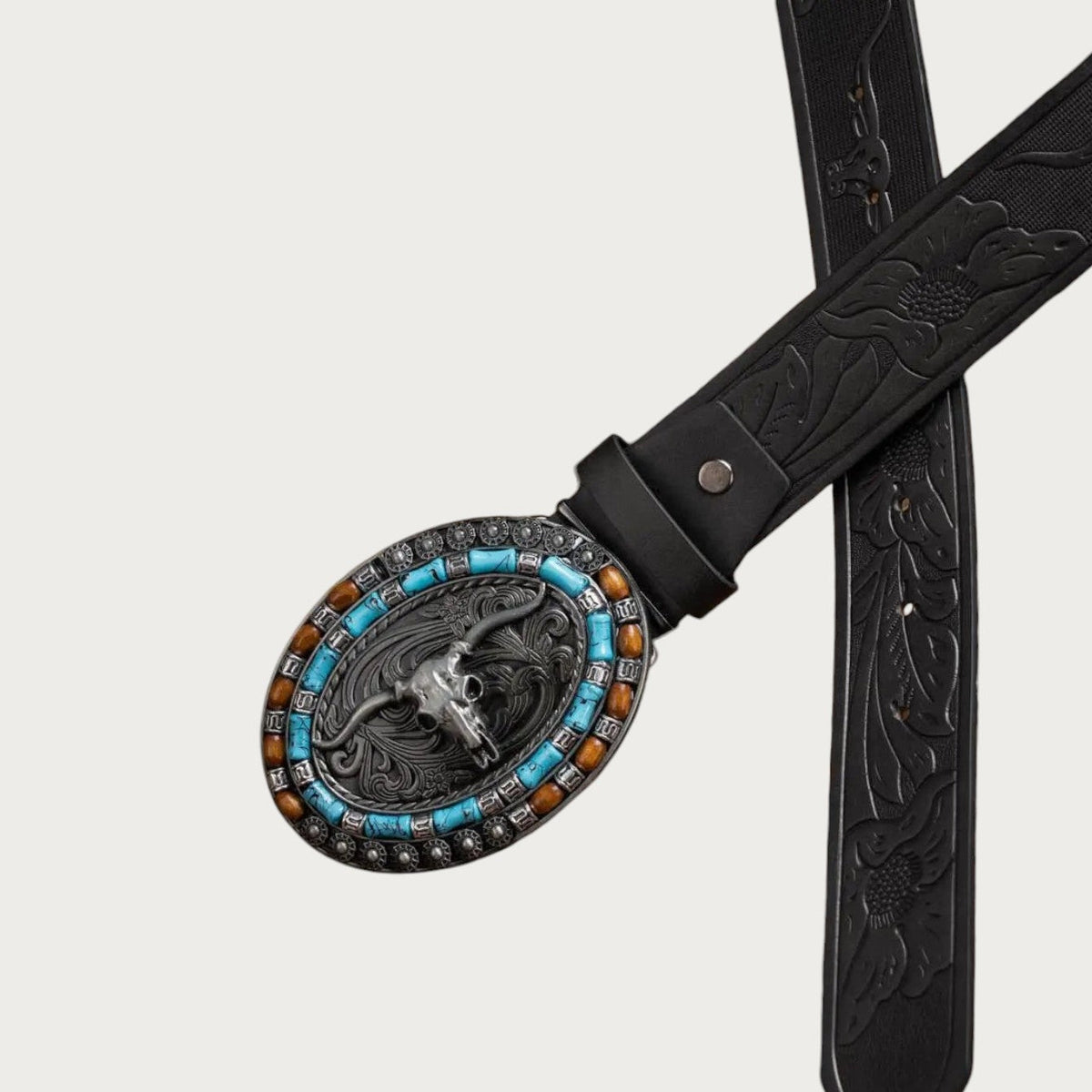 Deux sangles noires gaufrées croisées sous la boucle ovale longhorn turquoise et ambre de la ceinture Ceintura