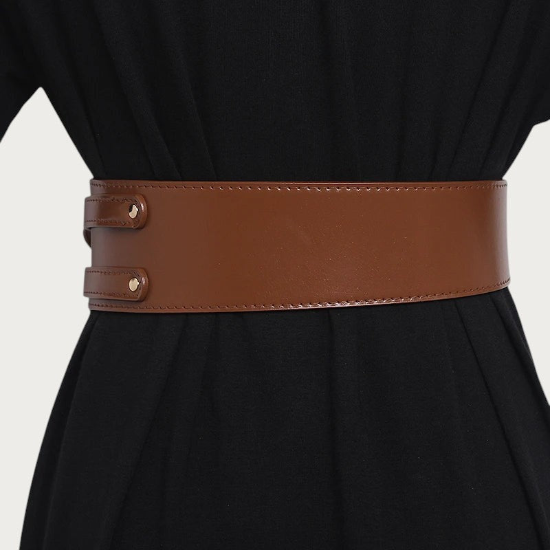 Ceintura large ceinture obi marron en cuir de vachette portée sur une robe noire pour un style élégant